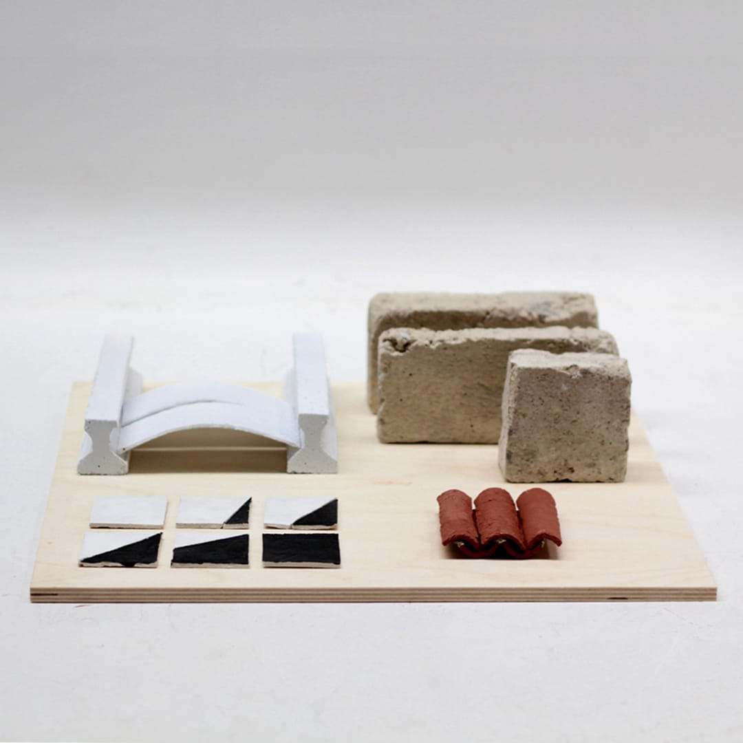 Material study for Can Lis: stone slabs, a curved white roof piece, tiles and terracotta pipes on a plywood board