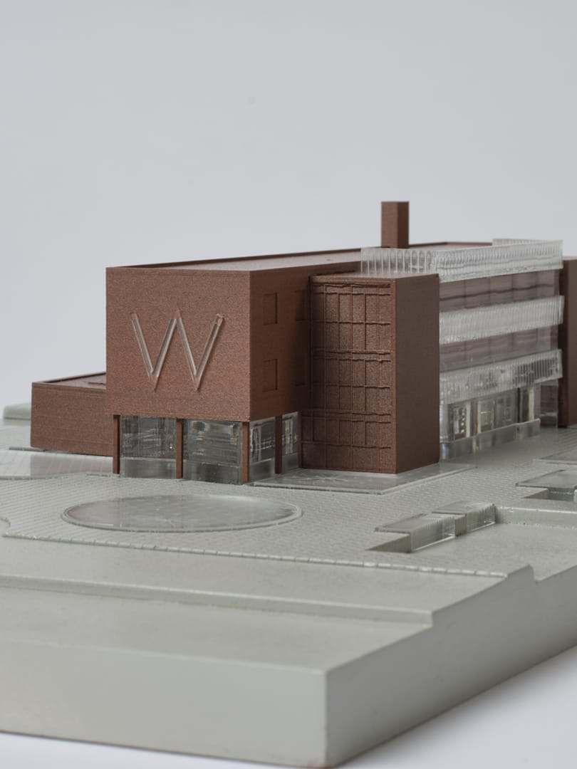 Close-up of the brick facade with the W relief, cast acrylic glazing and 3D-printed canopy