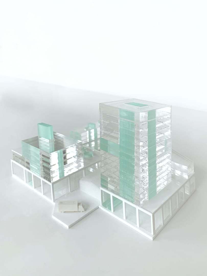 A transparent tower with green cores beside the lower blocks