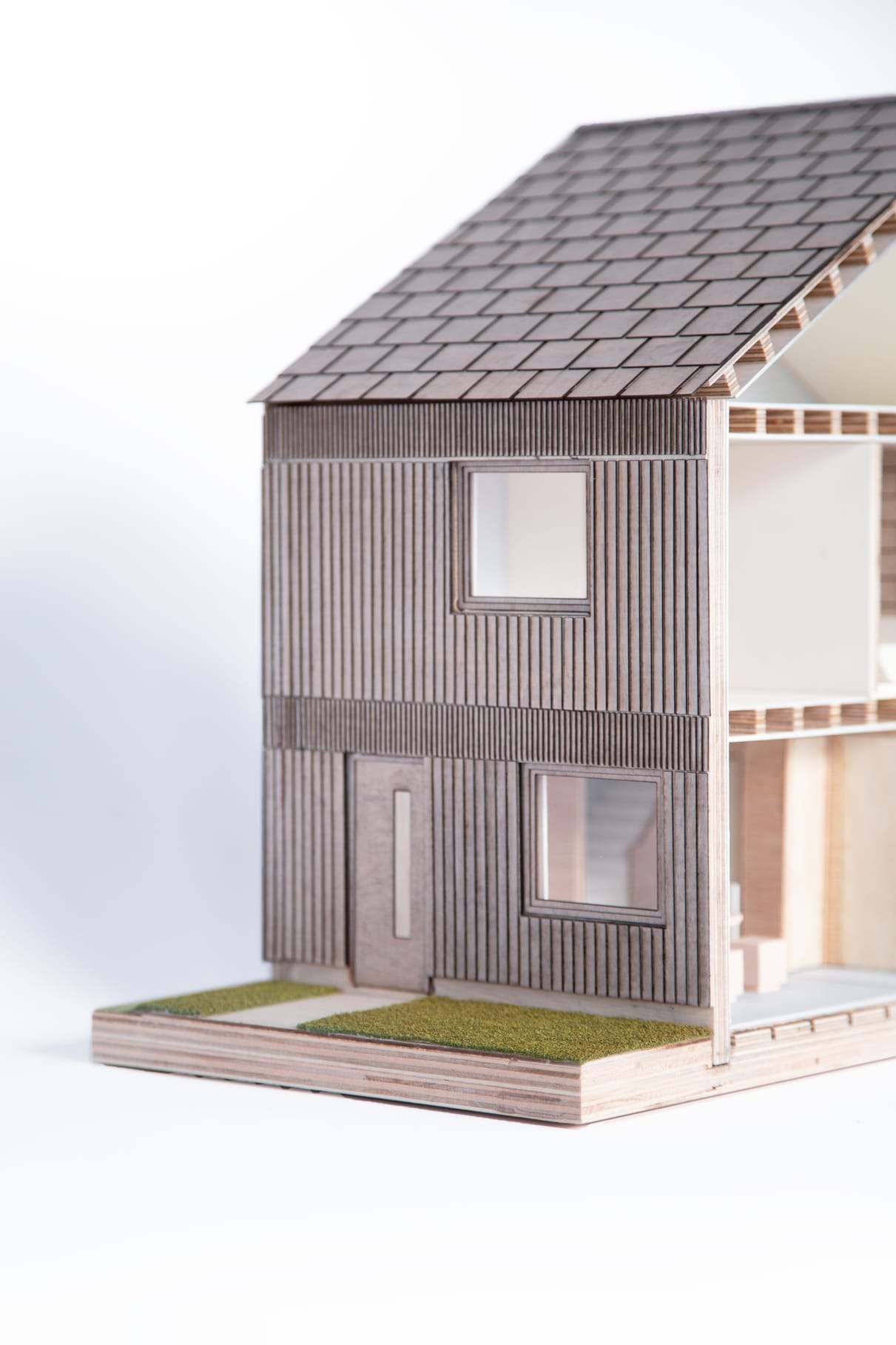 Close-up of the vertical timber cladding, the recessed front door and the tiled roof of the model