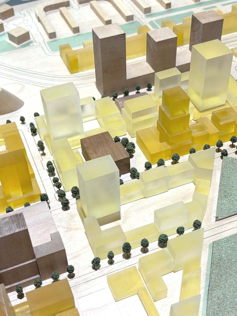 Amber acrylic volumes marking the new development among the timber blocks