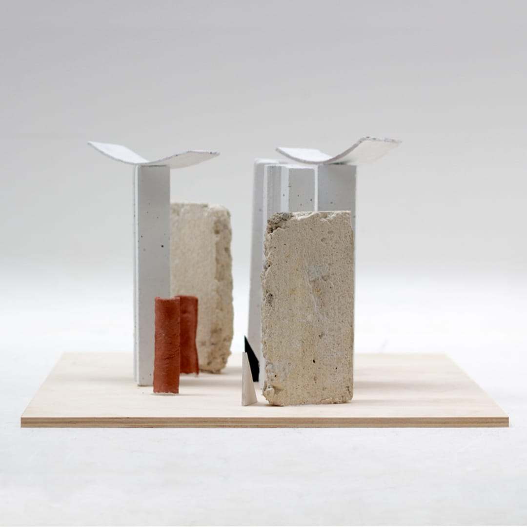Study model with two white roof pieces on stone and a terracotta cylinder