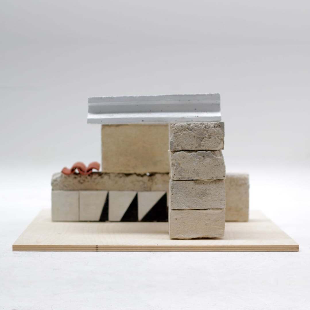 Study model combining stone blocks, tiles and a metal roof