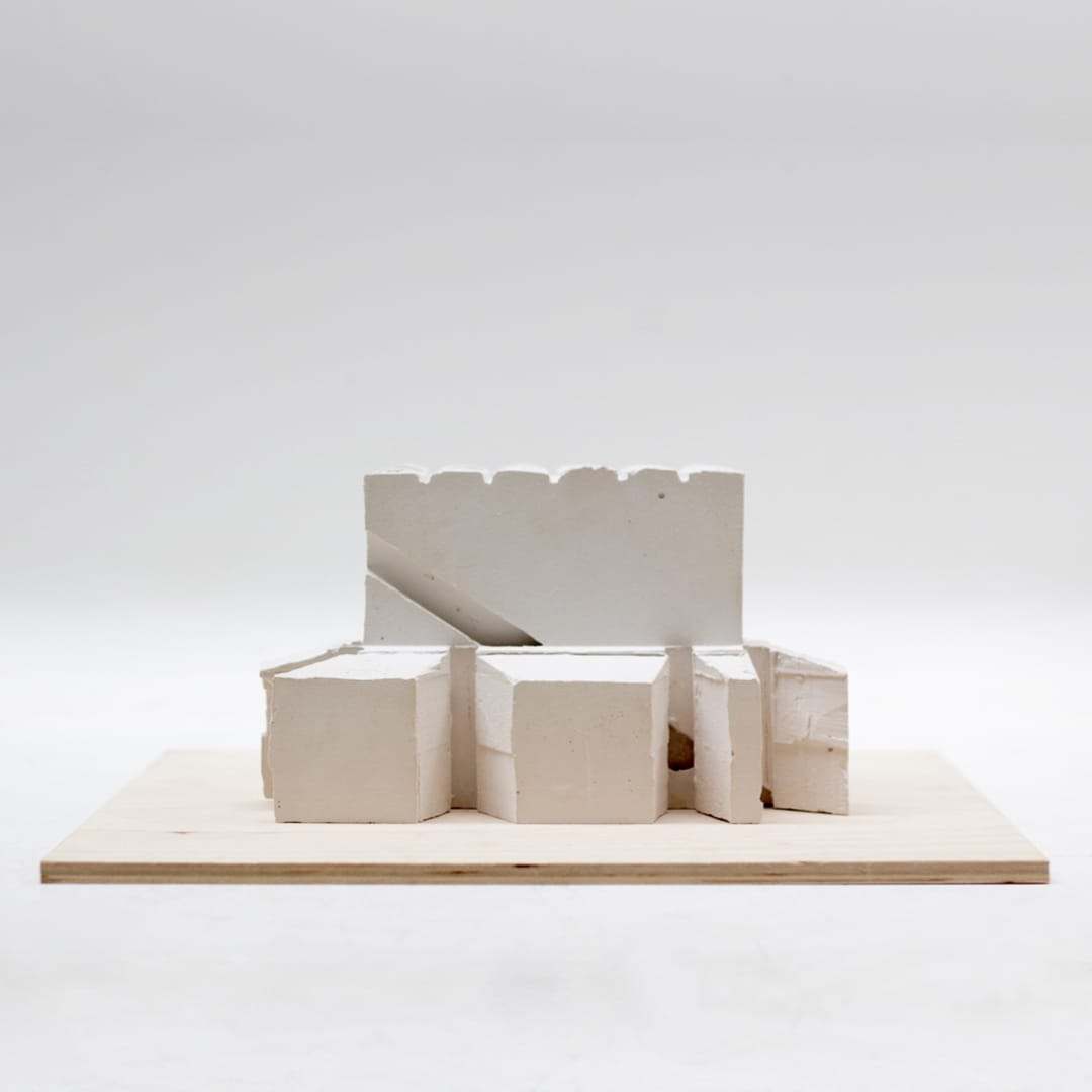 White plaster study model with a castellated wall on a plywood base