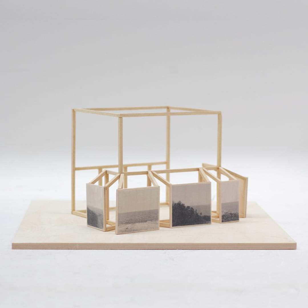 A wooden frame with small painted panels of sea and coast, on a plywood base