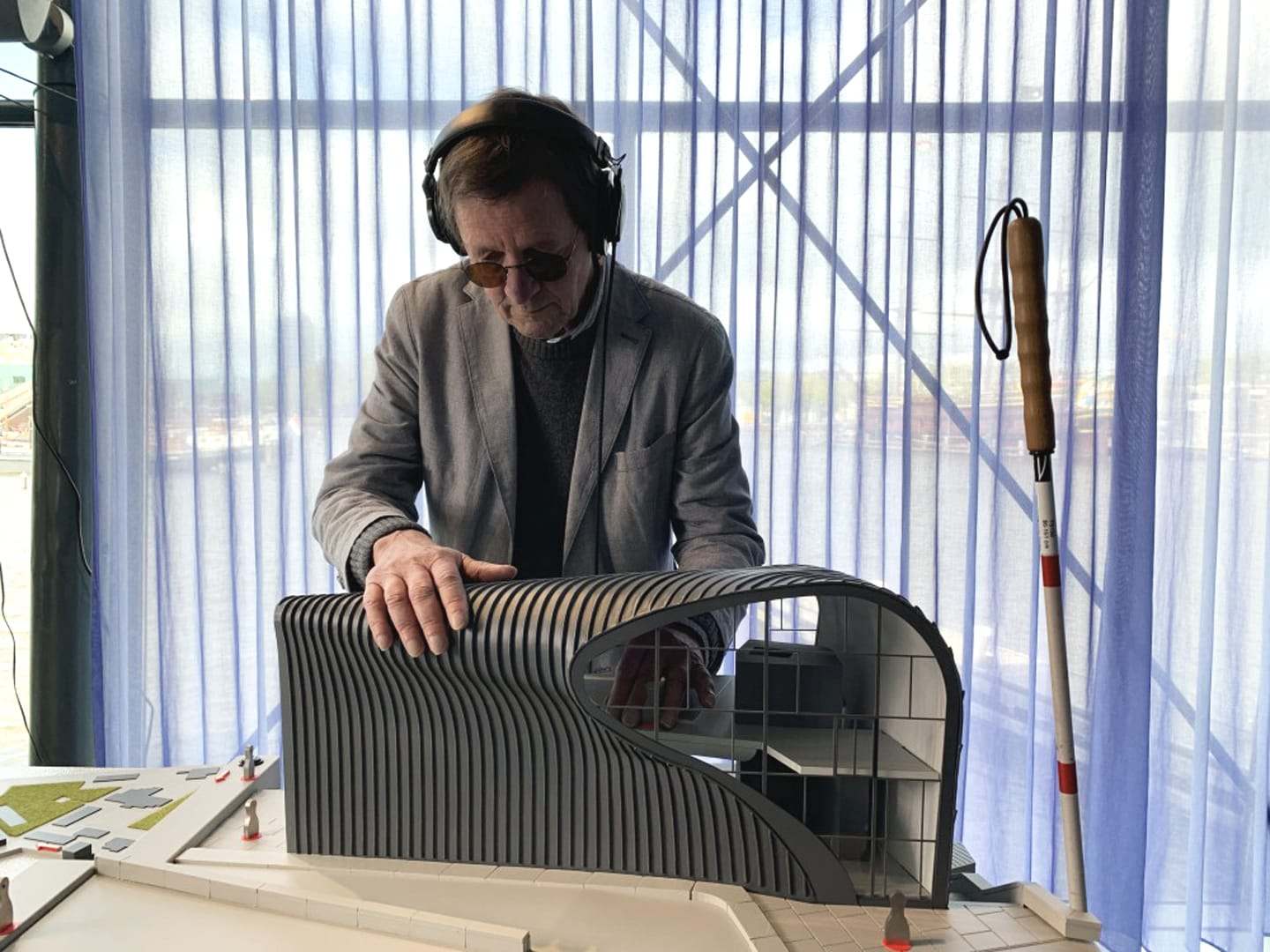 A visitor with headphones exploring the ribbed shell of the ARCAM model by touch