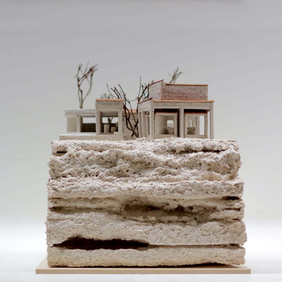 The Can Lis model: two small houses with dry branches on a rough, layered stone base
