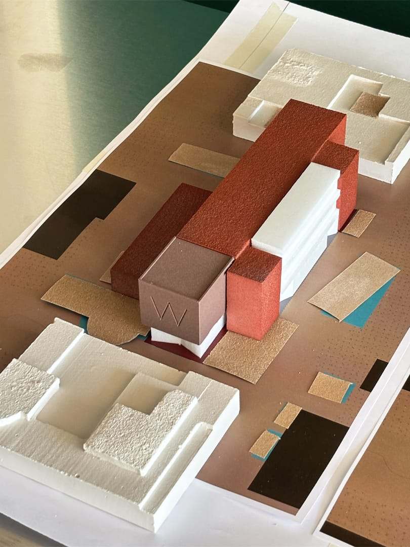Work in progress: coloured material samples laid out around the brick volume with the W relief