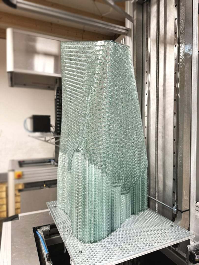 A twisting glass-like tower being 3D-printed in a resin printer