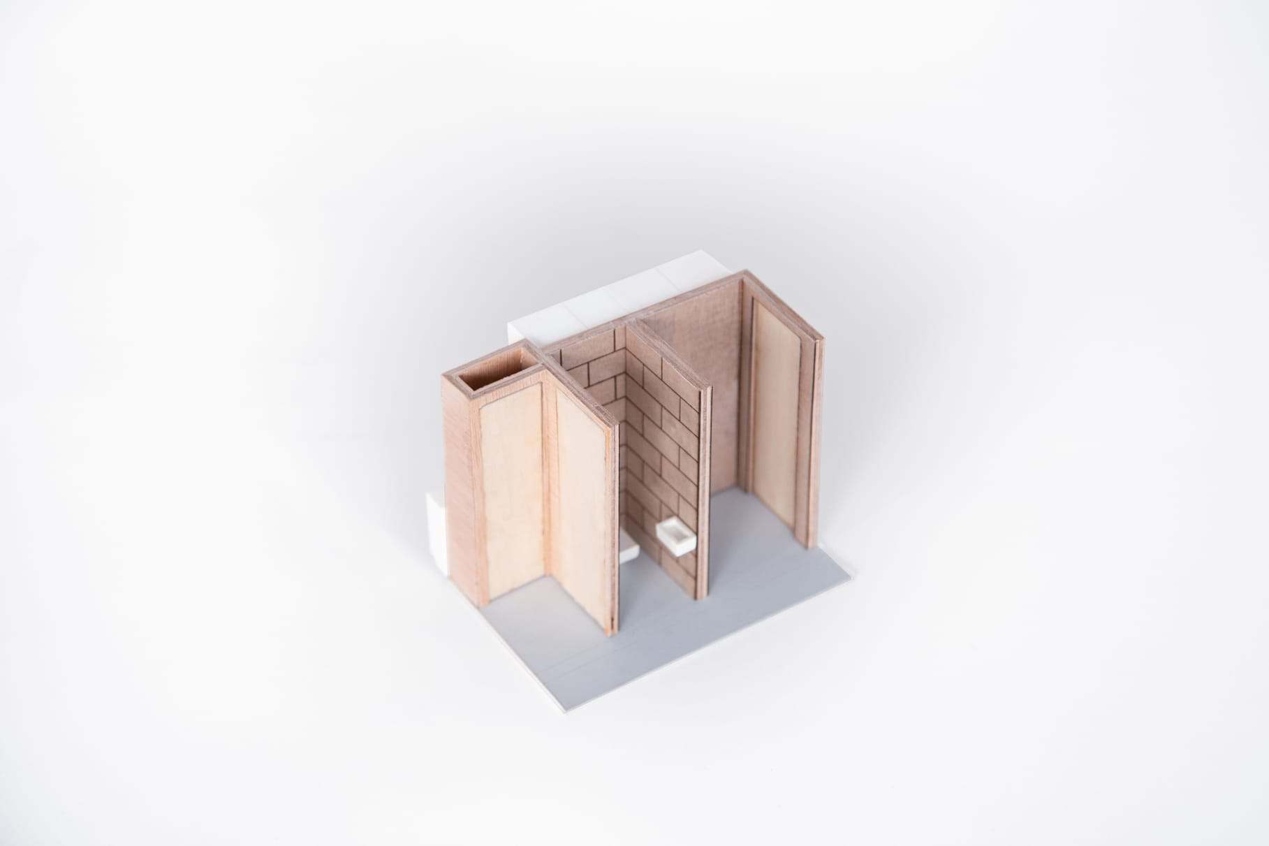 Detail model of a bathroom with a toilet behind a plywood partition, seen from above