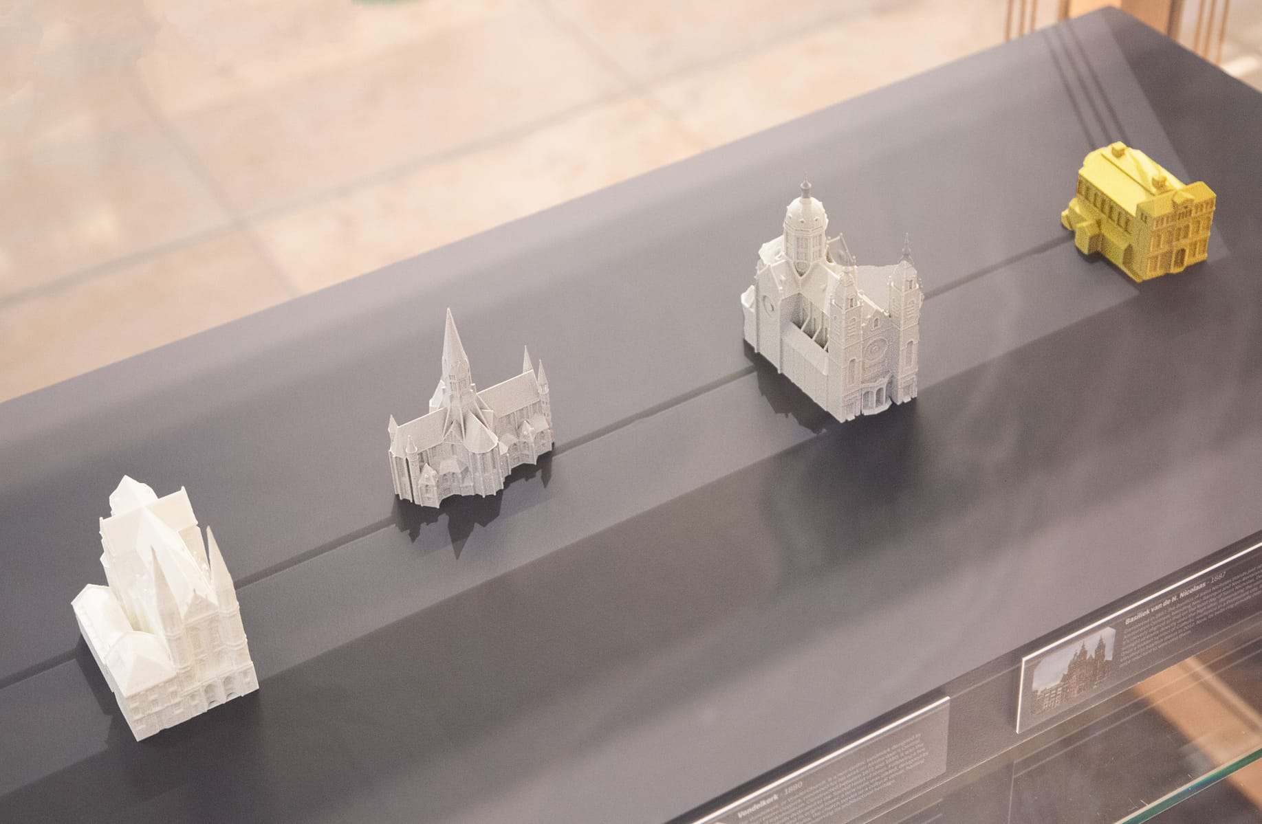 Four small white landmark models, including churches, on a display shelf