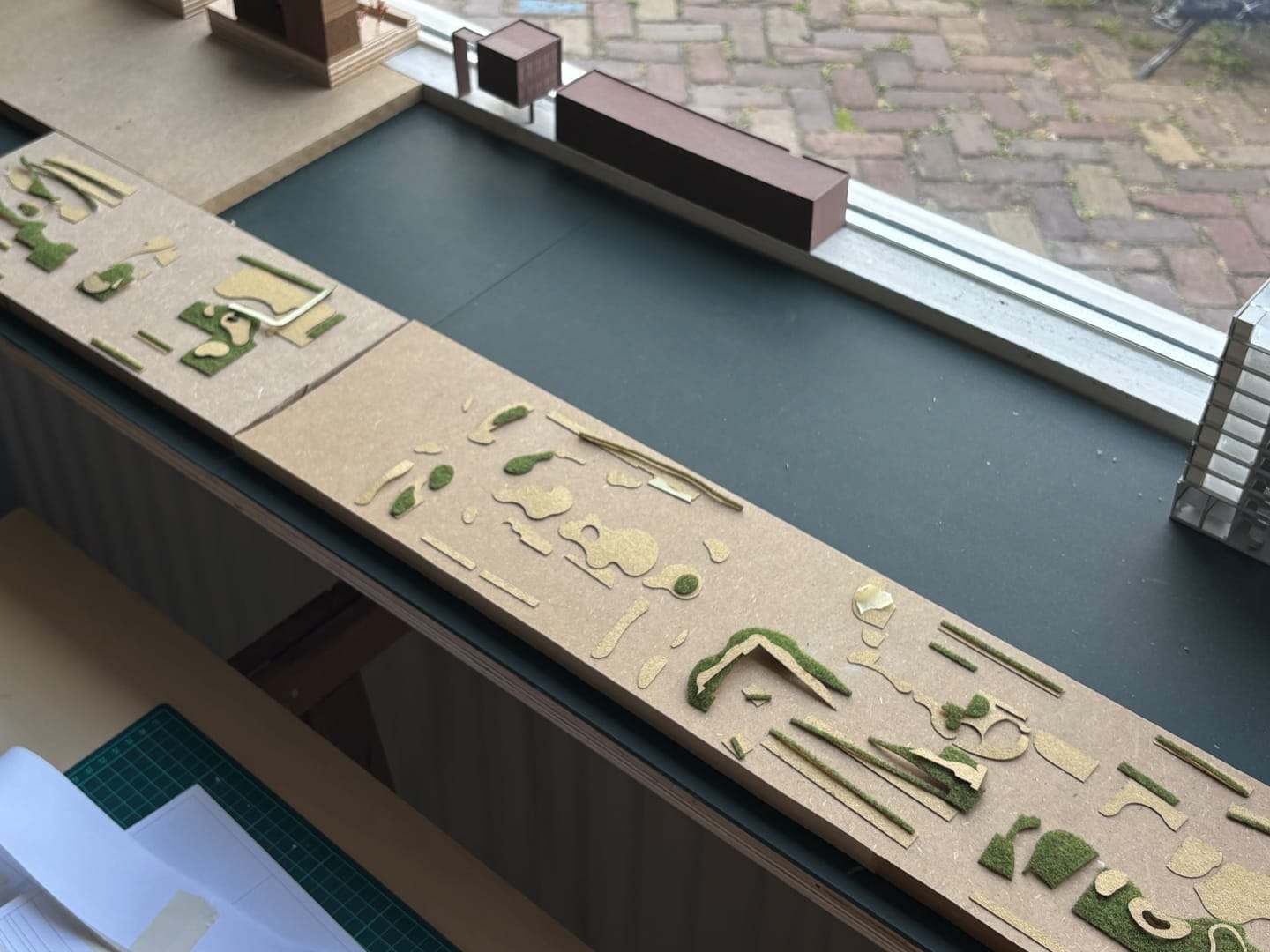 Landscape elements of the De Vonk model cut out in card along a dark canal