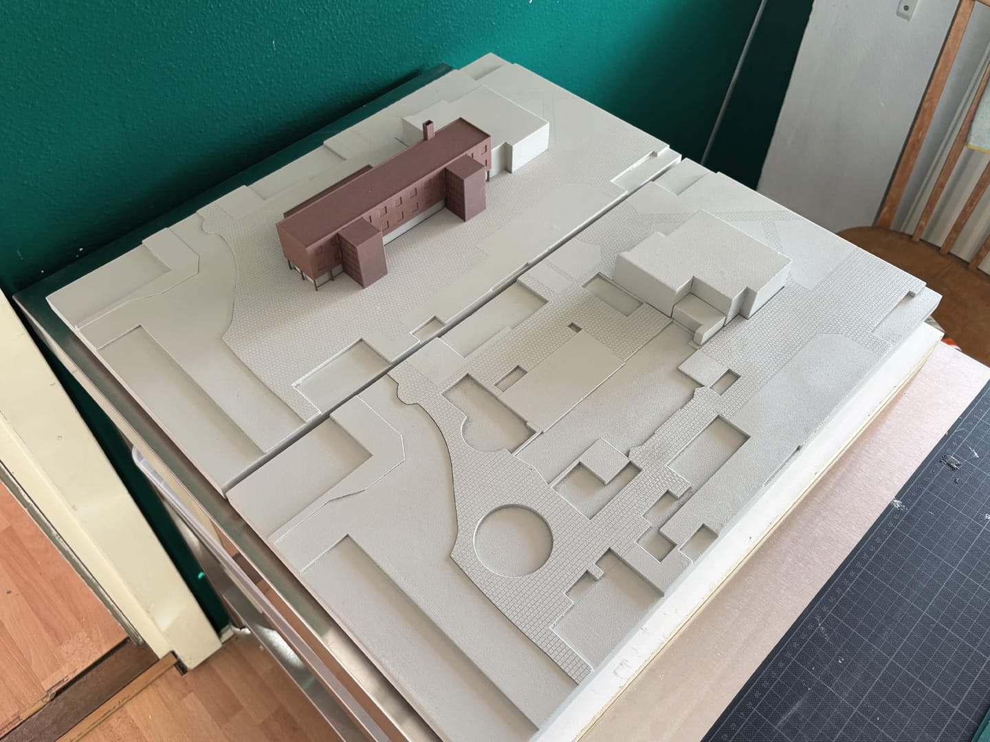 The finished white site base with the brown building set on it, in the workshop