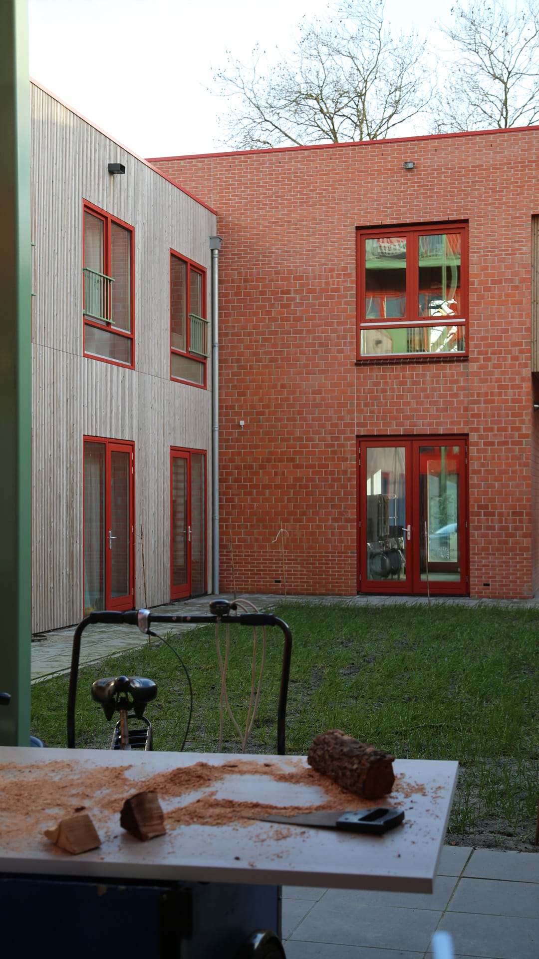 An insect hotel placed in a brick courtyard, with a workbench in the foreground