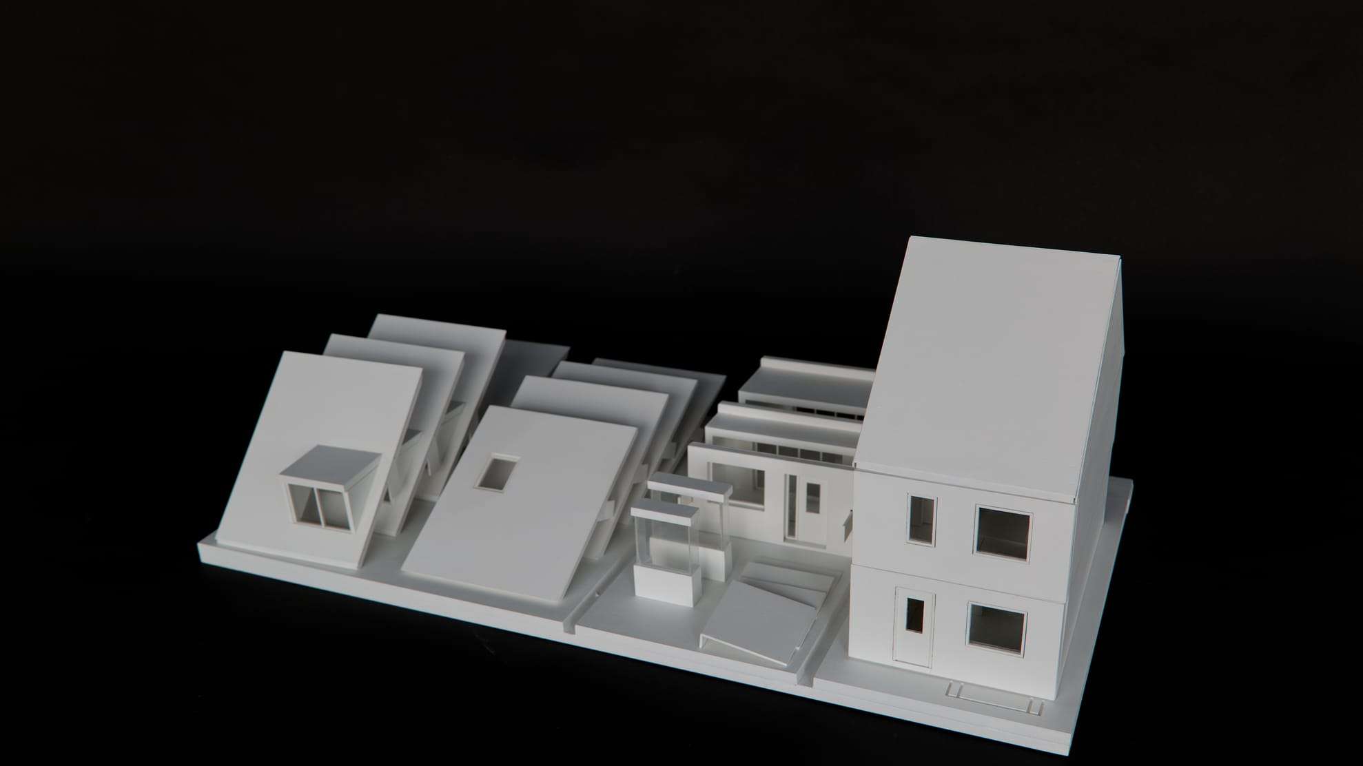 1:30 model of the Bolton Woning: white housing variants on a long base plate against a black background