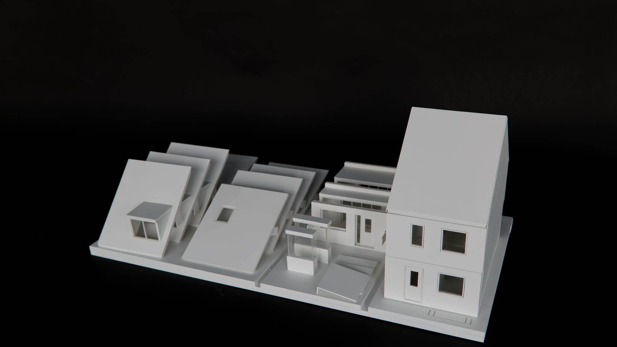 1:30 model of the Bolton Woning: white housing variants on a long base plate against a black background