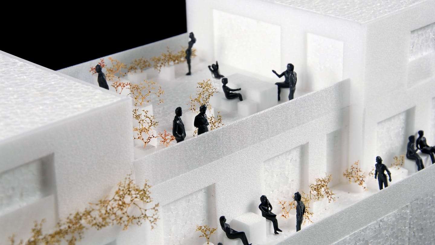1:50 concept model of the ZOHO housing block: white foam terraces with black figures and golden greenery