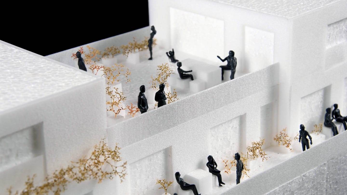 1:50 concept model of the ZOHO housing block: white foam terraces with black figures and golden greenery
