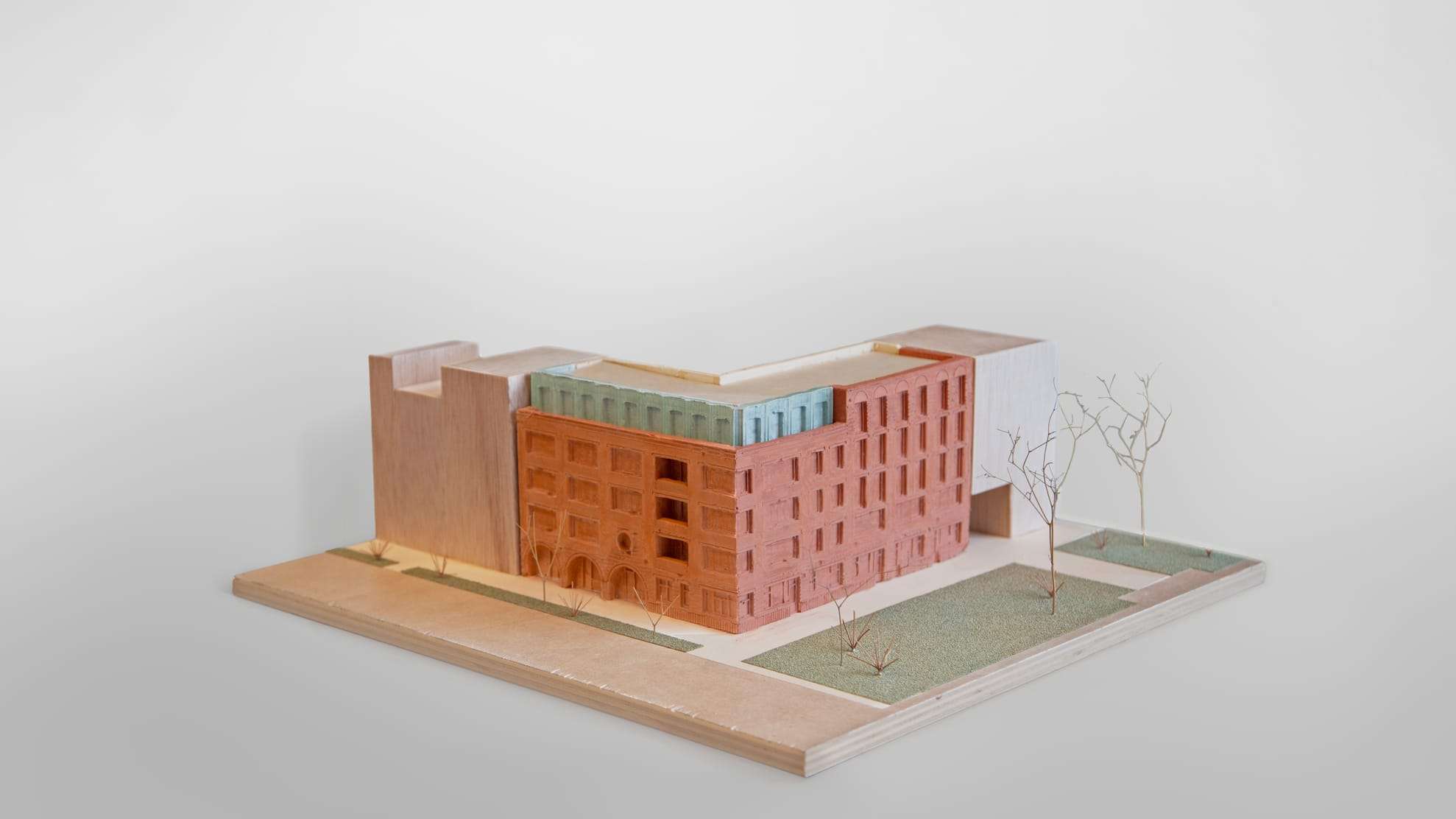 1:150 model of Bakstayn: a red-brick housing block with a pale roof on a plywood base