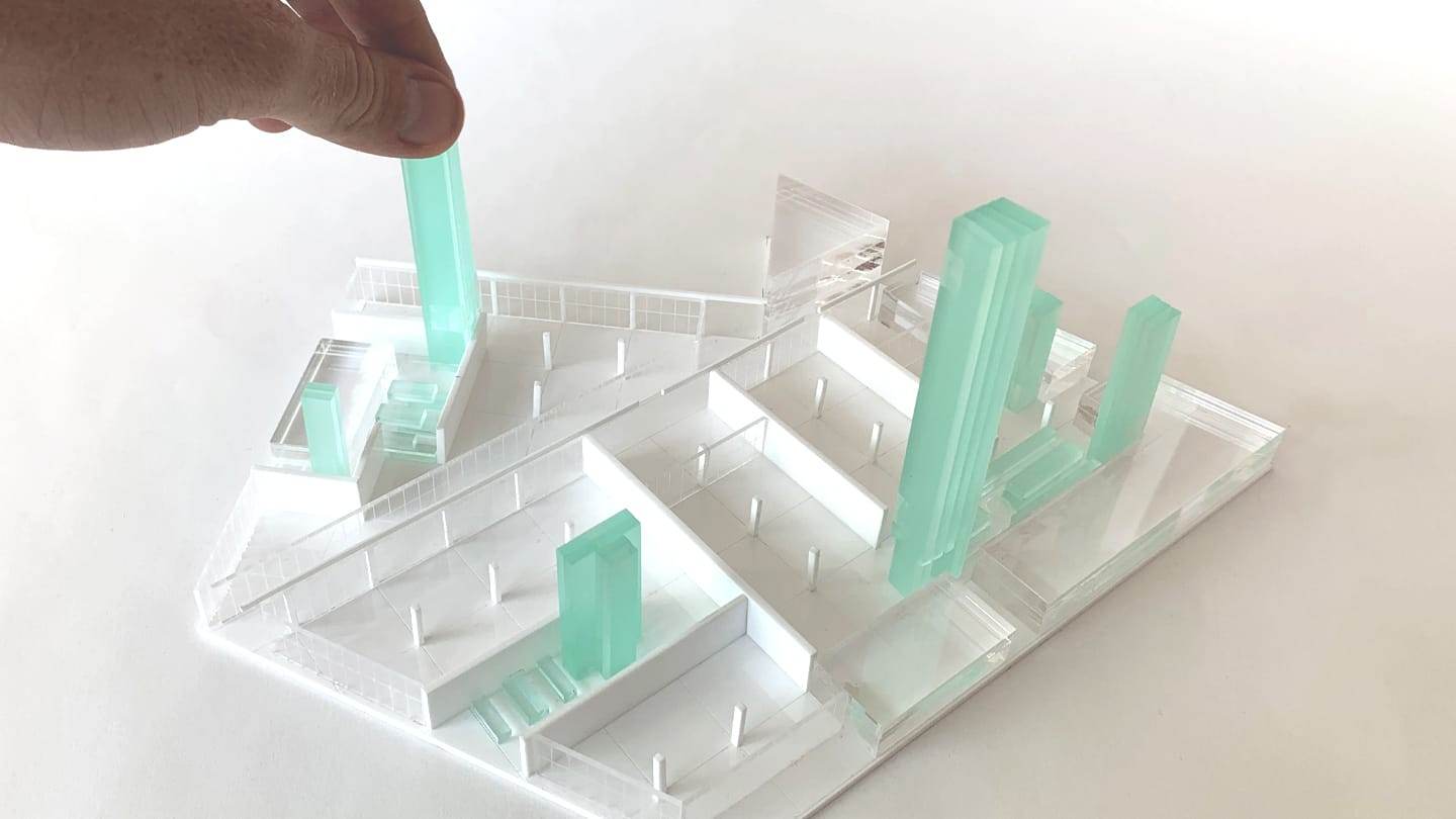 A hand placing a green acrylic core into the white grid of the model