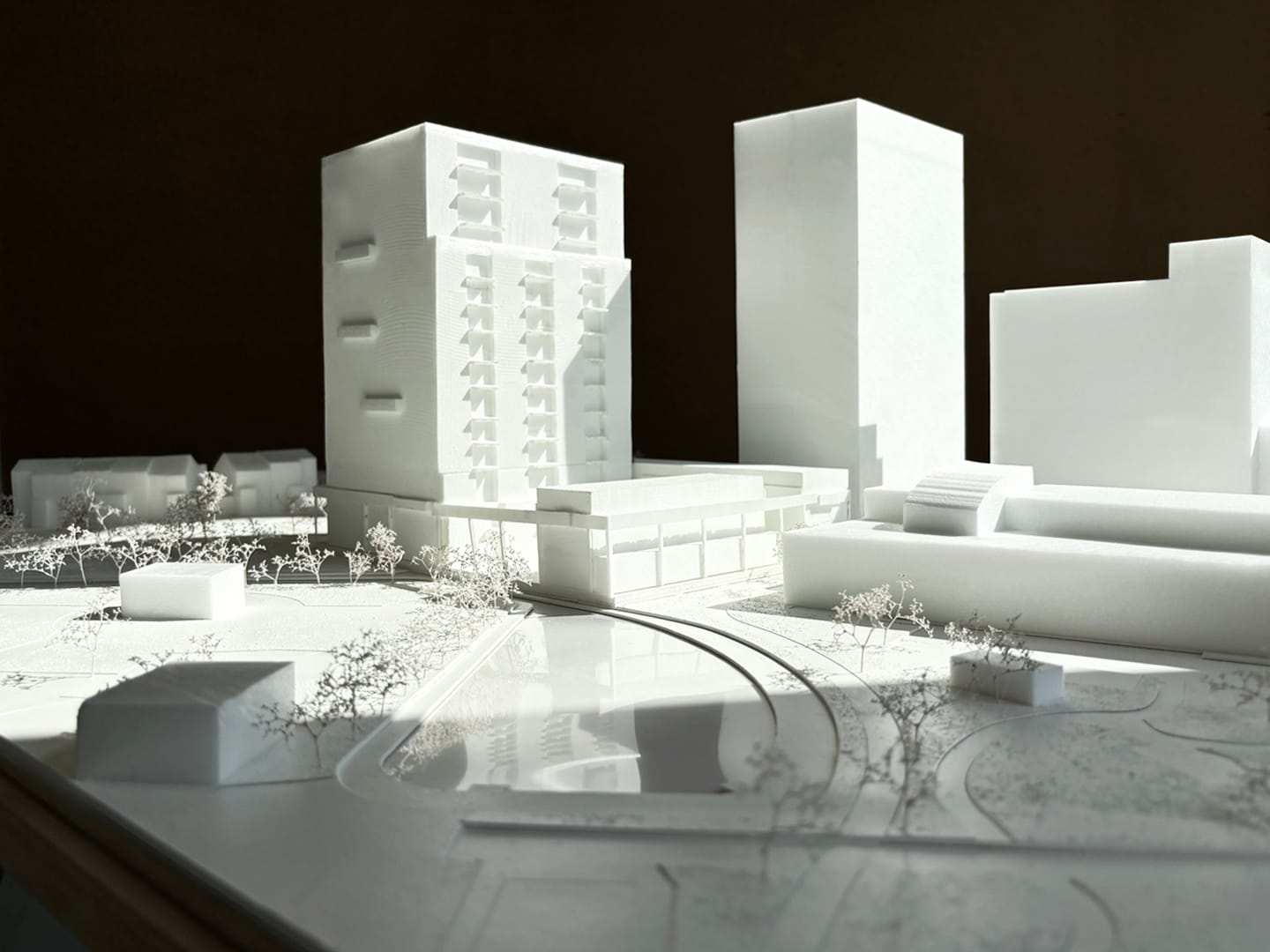 1:200 presentation model of Bliek: white building volumes and trees on a white site base in raking light