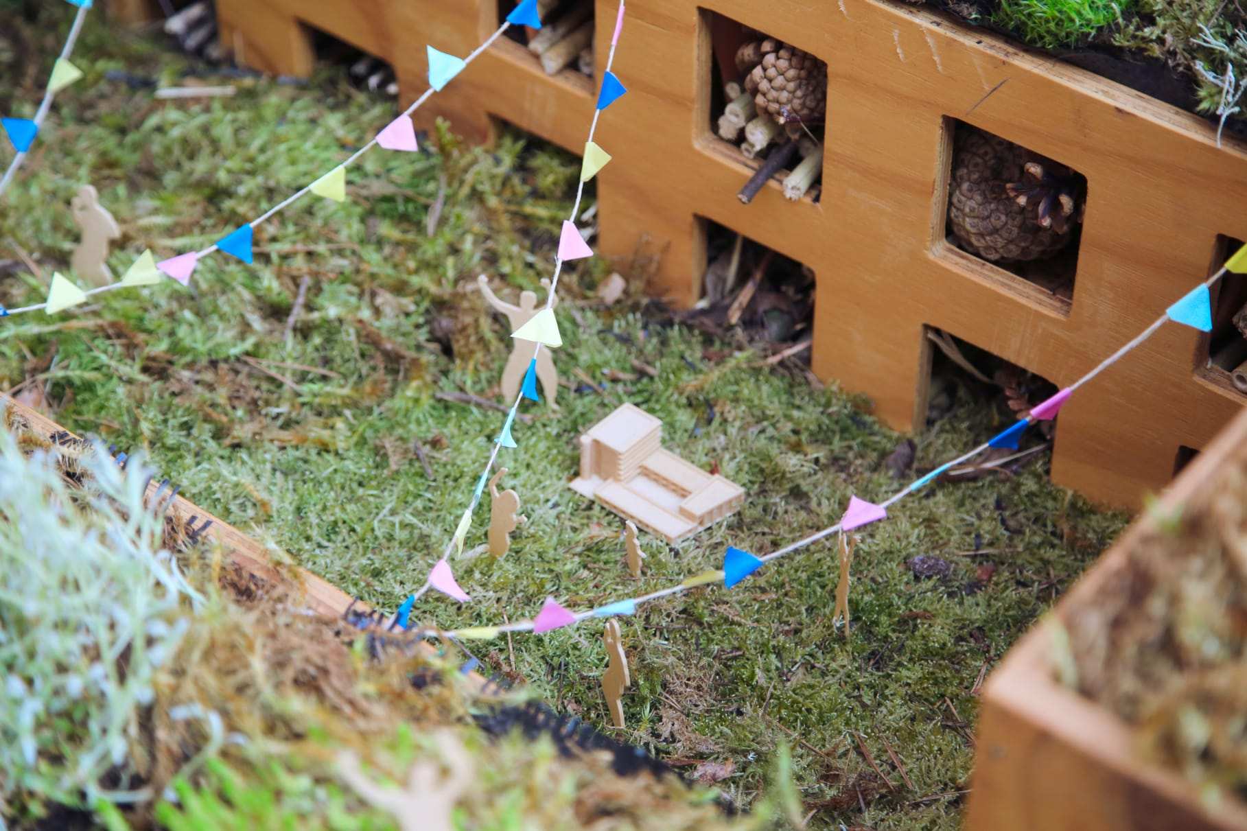 Bunting strung over the moss roof, with small scale figures among the planting